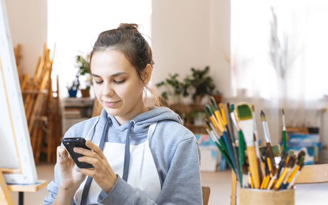 Lady using her phone for finances in front of an easel