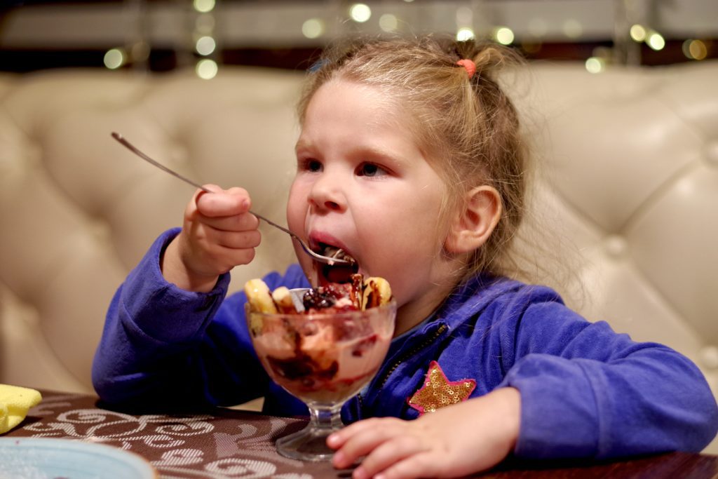 Girl eats ice cream with toppings